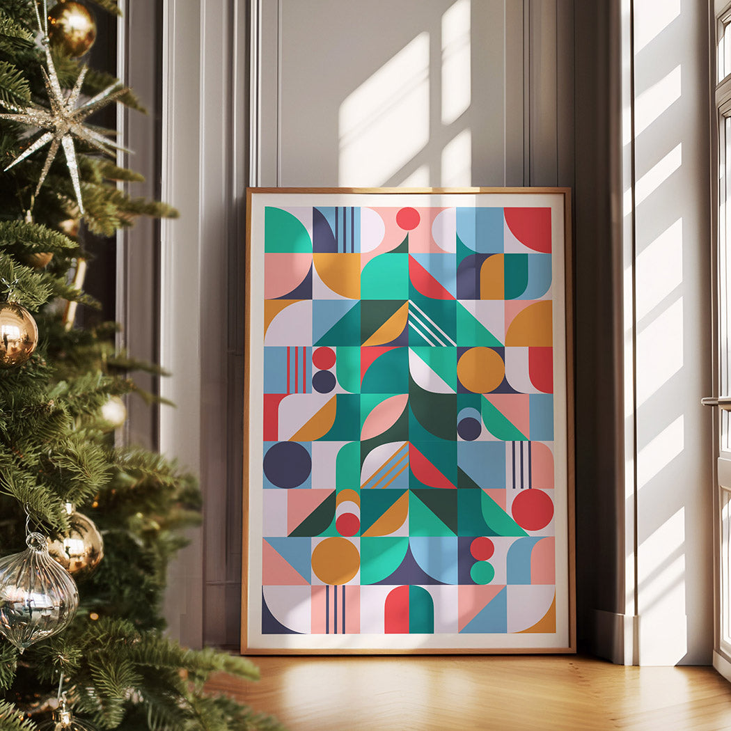Festive framed poster with geometric shapes, placed in front of a beautifully decorated Christmas tree.