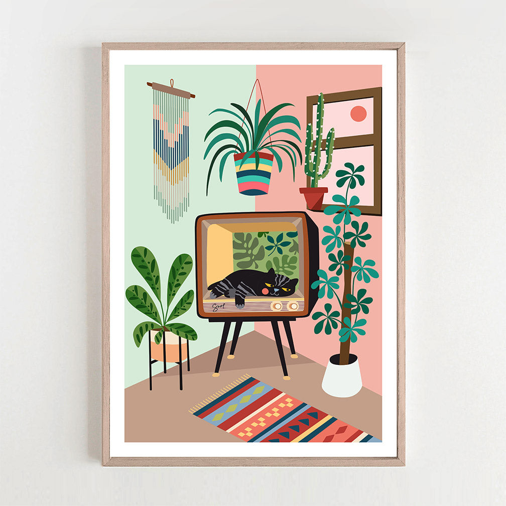 A cat and green plants print framed on a white wall