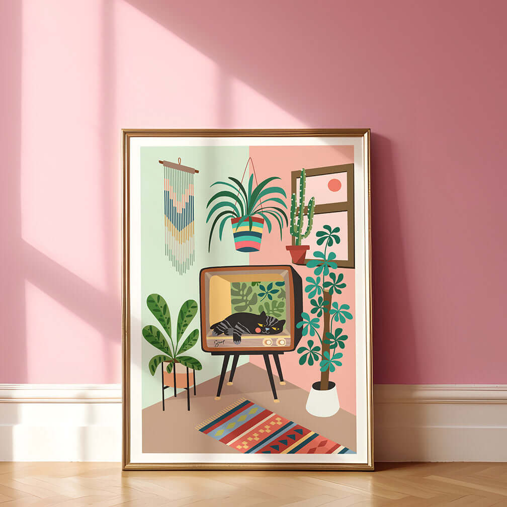 A cat and green plants print framed on a pink wall