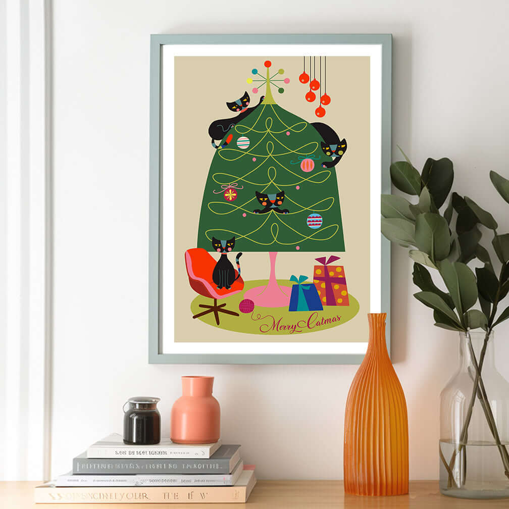 A festive framed print of a black cat perched on a Christmas tree.