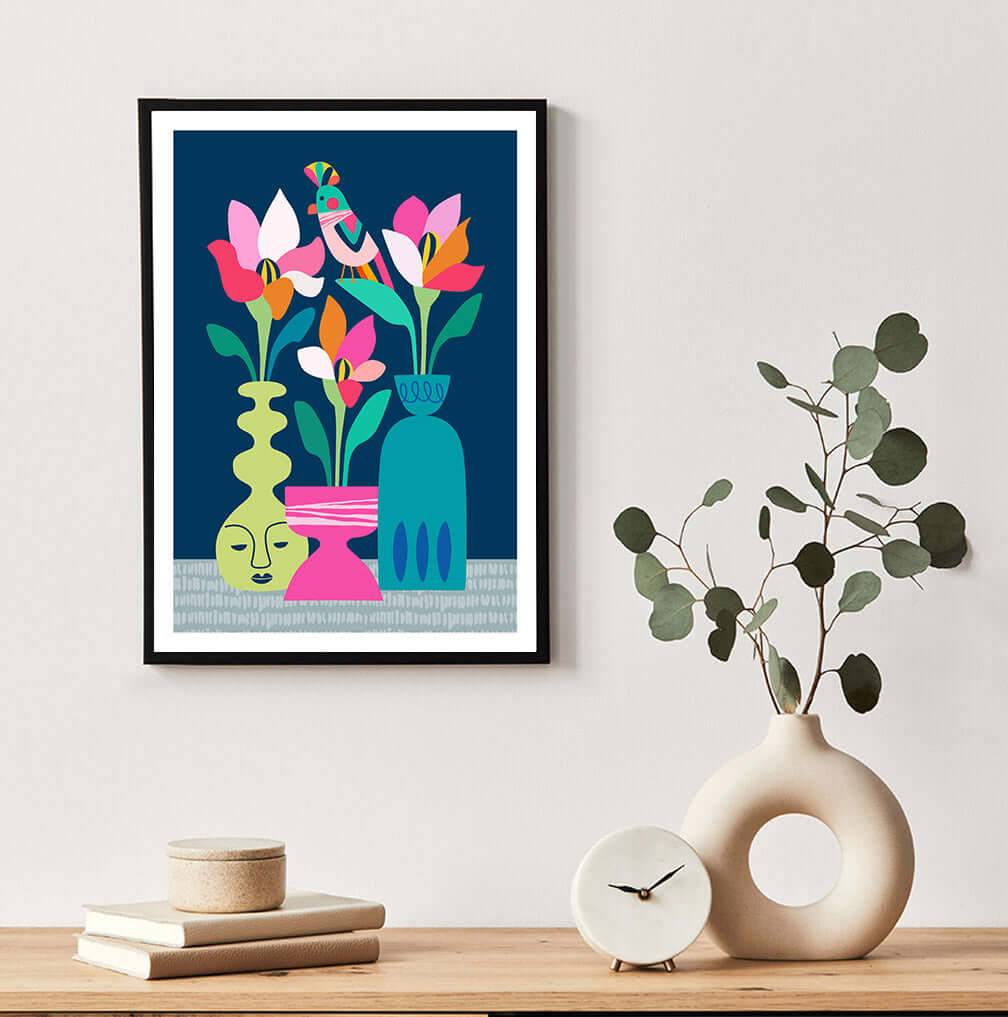 Colorful floral print with flowers in vase design hanging on wall with some books and a clock..