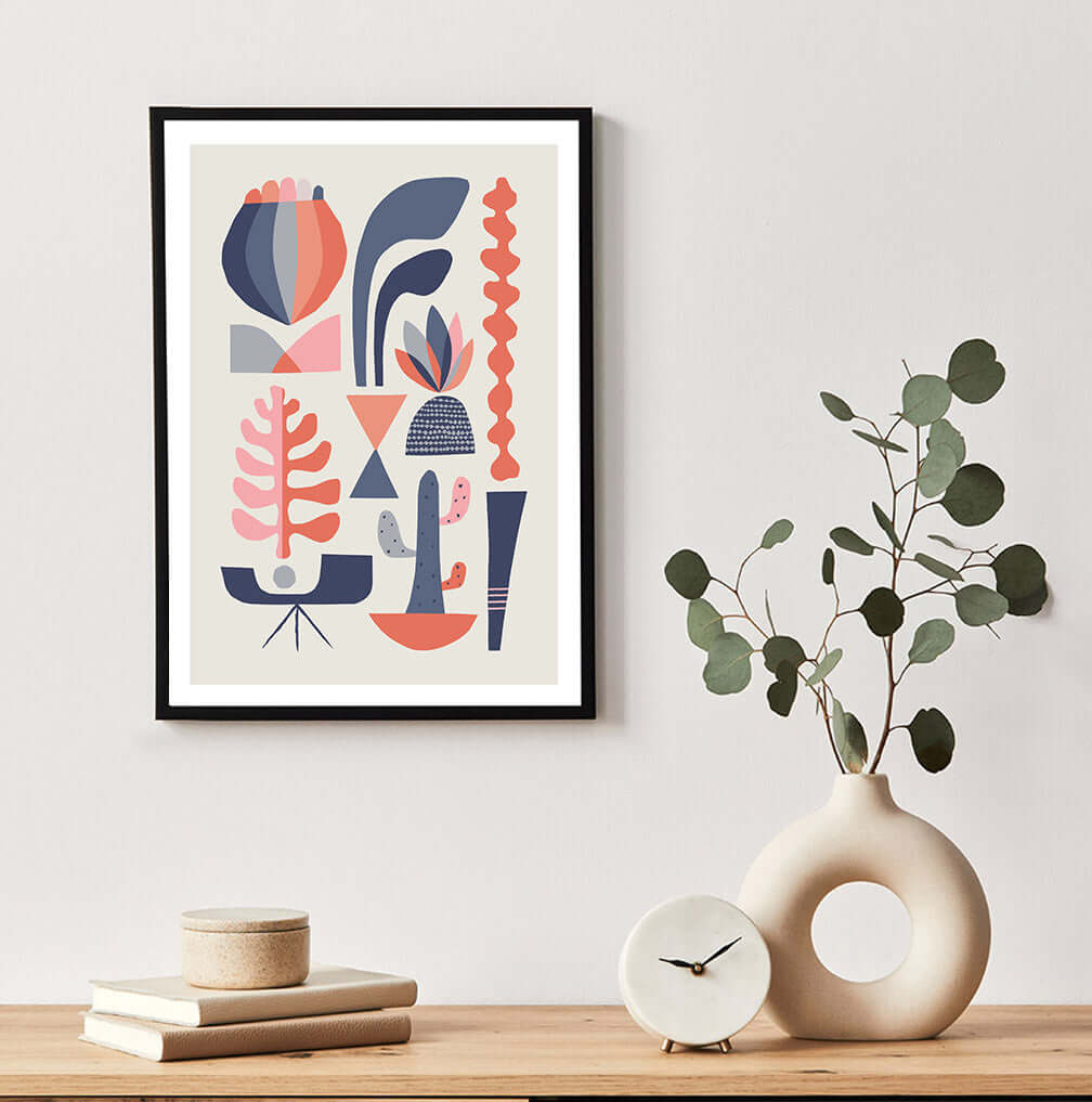 A framed abstract succulents art print with a plant and a clock on a table.