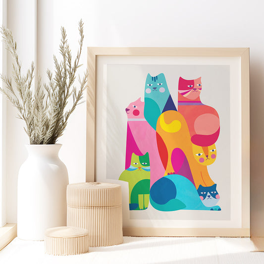 Framed colorful cat illustration on a white wall with decorative items.