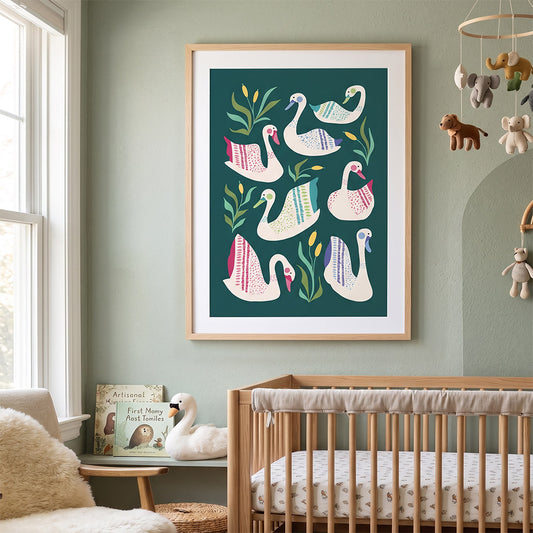 A framed art print featuring stylized white swans with pink, blue, and green patterns on a dark teal background, displayed on a sage green wall above a wooden baby crib in a softly styled nursery.
