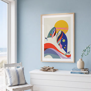 Bright coastal room with pale blue walls, ocean view, white dresser, striped chair, driftwood decor, and colorful abstract fish artwork.